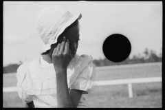 1135_ African American young lady with hat, at the horse- races.