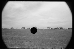 1976_Heavily vignetted image of field with houses in the distance