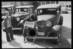 2500_ Boys selling newspapers perched on the front wing of a Ford  4 door sedan