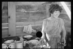 2073_Twelve-year old girl of family of nine, cooking meal in-open lean-to  hut, Tennessee