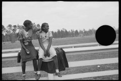 1185_Two black-American girls enjoying sitting on the rails at the probable race-track