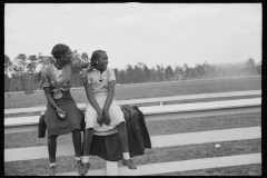 1185_Two black-American girls enjoying sitting on the rails at the probable race-track