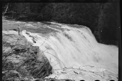 1619_ Man on rock observing river in spate ,Fall Creek