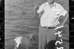 1852_Man with  dog standing beside a stretch of unidentified water.