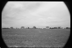 1976_Heavily vignetted image of field with houses in the distance