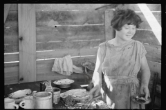 2073_Twelve-year old girl of family of nine, cooking meal in-open lean-to  hut, Tennessee